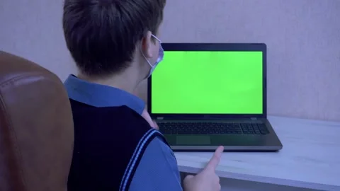 Guy drumming his fingers on the table while sitting at a laptop in a protective Stock Footage 149701142