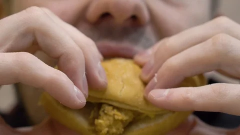 Guy eating a chicken burger 스톡 동영상 114753684