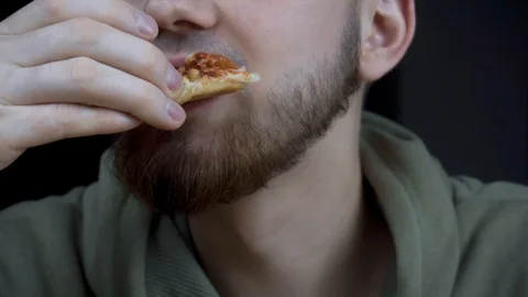 The guy eats delicious pizza. close-up of a mouth chewing a slice of pizza. 스톡 동영상 120757072