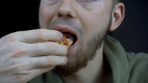 The guy eats delicious pizza. close-up of a mouth chewing a slice of pizza. Видео 120757075