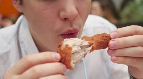 Guy eats fried chicken in a fast food restaurant closeup Vidéo 68714114