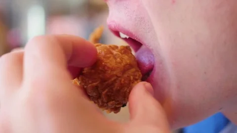 Guy eats fried chicken in a fast food restaurant closeup 库存影片 75874882