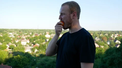 The guy eats fruit in the summer park Stock Footage 114821491
