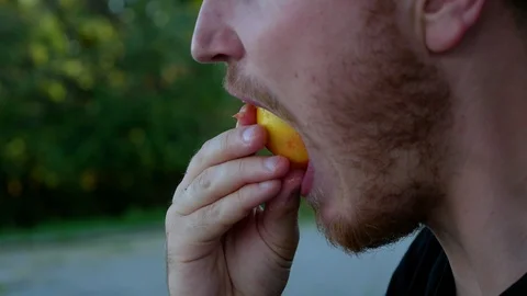 The guy eats fruit in the summer park Stock Footage 114822333