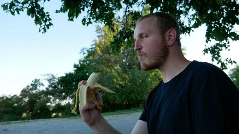 The guy eats fruit in the summer park Stock Footage 114822412