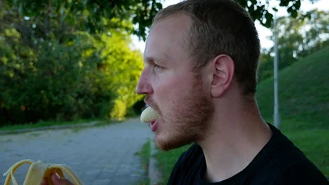 The guy eats fruit in the summer park Stock Footage 114822757