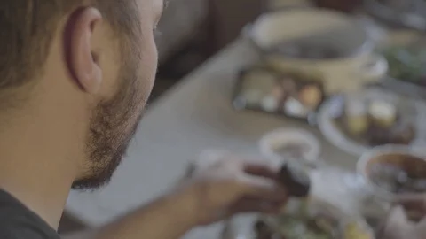 A guy eats meat, puts sauce on a piece of meat, watches a movie on a smartphone Stock Footage 129101270