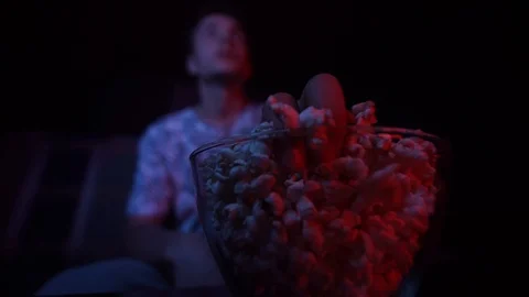 The guy eats popcorn and watches TV.Focus on popcorn Stock Footage 126093236