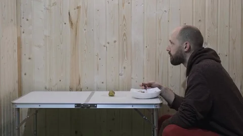 Guy eats sitting at the table and on the table jumps black cat Stock Footage 119787188