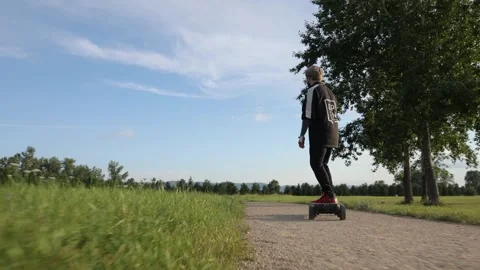 A guy on an electric longboard rides through the park ecology transport nature Stock Footage 260867120