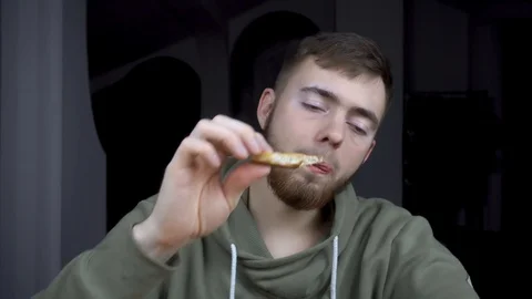 The guy enjoys eating a slice of pizza. bearded man eating fast food. 库存影片 120757074