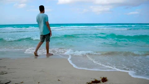 Guy enters the ocean with waves, with strong winds Stock Footage 130872641
