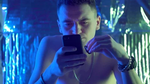 A guy of European appearance inserts wireless headphones in his ears Vidéo 123574740