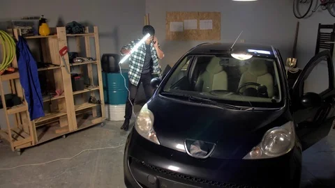A guy examines a car with a lamp Stock Footage 127430419