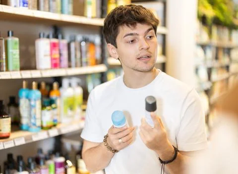 Guy examines roll on deodorant, makes purchase decision, doubts correctness of Stock Photos