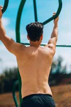 Guy exercising arms doing hard exercises on metal bars 写真素材