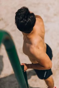 Guy exercising arms doing hard exercises on metal bars 库存照片