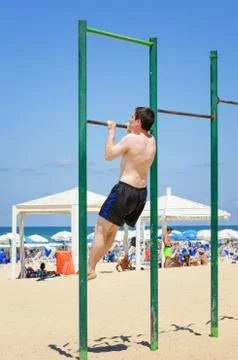 Guy exercising on pull up beach bar Stockfoto's