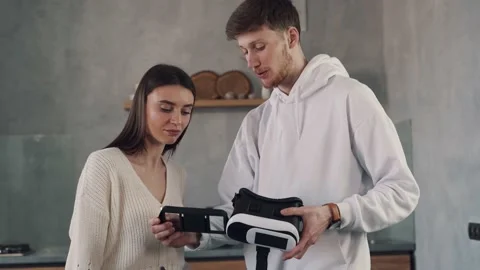 The guy explains to the girl how virtual reality glasses work. Virtual reality Stock Footage 153244672