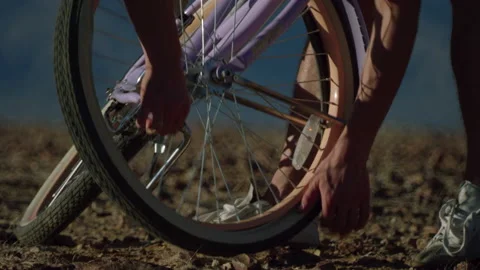 A guy fall, fixes a camera on a bicycle in a rocky desert area without tools Stock Footage 193651617