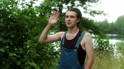 A guy in a farm jumpsuit waves someone's hand as a sign of greeting. Stock Footage 197480207