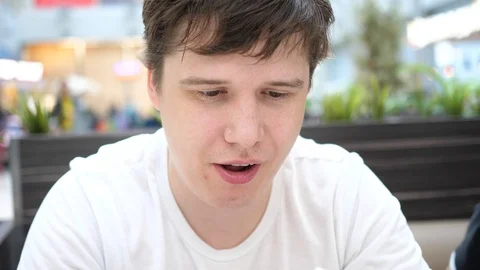 The guy in the fast food restaurant eats fried potatoes on a plate. Face close 库存影片 107860480