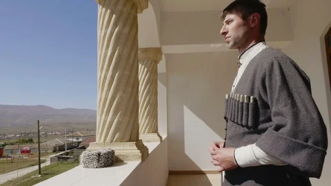Guy fastens buttons on Dagestan circassian on balcony Stock Footage 108167390
