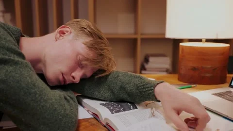 Guy fell asleep while doing homework at the table, lying on books, side view Vídeo Stock 164380822