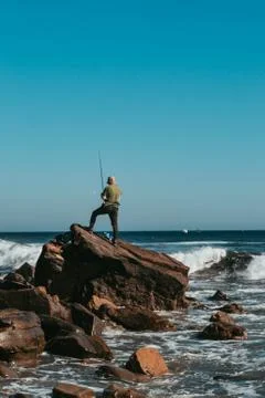 A guy is fishing on the rock Foto stock