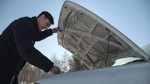 Guy fixing a car outside in sunny winter day Stock Footage 125762163