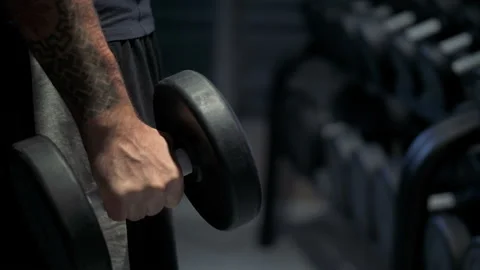 Guy flexing arms with dumbbells in his hands, gym workout Video stock 103372928
