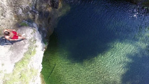 Guy flip jumps from rocks into mountain like and swims Video stock 91041928