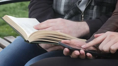 Guy flips through the book while the girl uses the phone Video stock 90183151