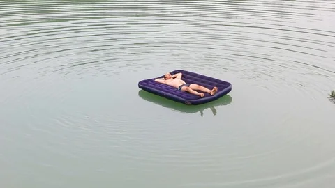 The guy is floating on an inflatable mattress Stock Footage 94701828