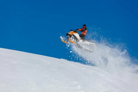 The guy is flying and jumping on a snowmobile on a background of blue sky Stock Photos