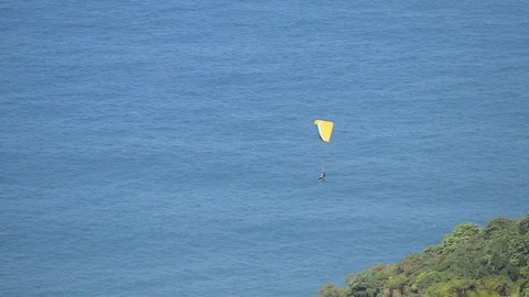 A guy flying on a paragliding, close to a forest, over the ocean Stock Footage 91753347