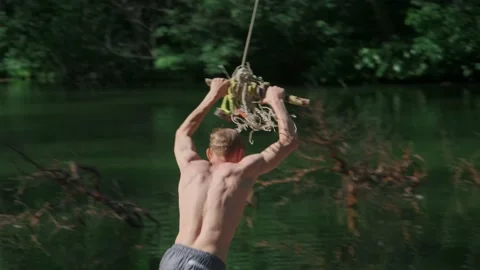 The guy in the forest rides over the water bungee on a tree, jumps into the lake Stock Footage 198050949
