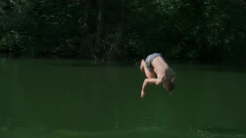 The guy in the forest rides over the water bungee on a tree, jumps into the lake Stock Footage 198051607