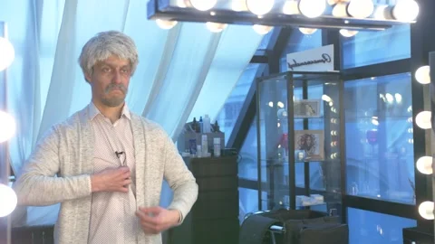 Guy in front of the mirror hides the microphone on his shirt behind a sweater Stock Footage 136154589