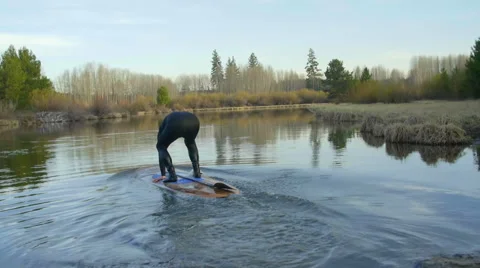 Guy gets on board and starts paddling away Stock Footage 63385980
