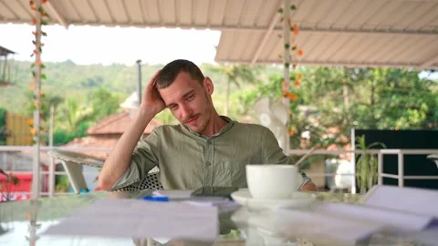 The guy gets nervous and throws the phone on the table and takes a sip of coffee Stock Footage 231336881