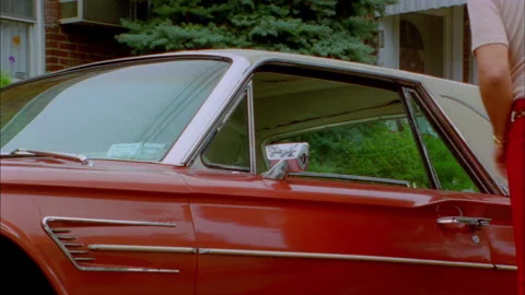 A guy gets into a Red Thunderbird 1960s 1970s Stock Footage 272259425