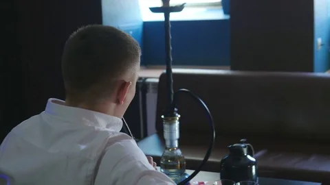 The Guy with The Girl is Sitting on The Sofa in The Cafe and Smoking a Hookah Stock Footage 75259489