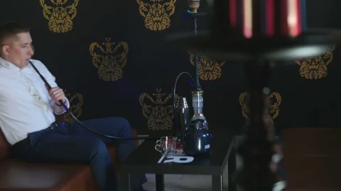 The Guy with The Girl is Sitting on The Sofa in The Cafe and Smoking a Hookah Stock Footage 75259562