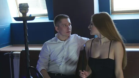 The Guy with The Girl is Sitting on The Sofa in The Cafe and Smoking a Hookah Stock Footage 75260102