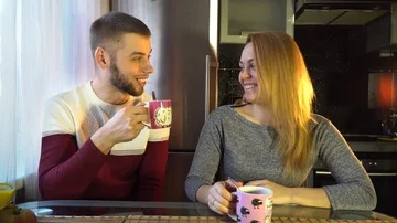 Guy with a girl, talking to each other in the kitchen and drinking tea Stock Footage 86150116