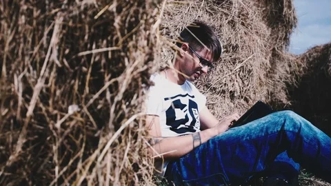 The guy with glasses among the many haystacks working in a laptop Video stock 72923314