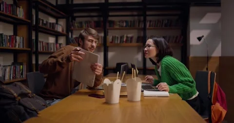 A guy with glasses communicates with his colleague an Asian girl and shows a Stock Footage 313356399
