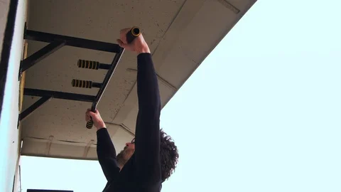 A guy with glasses does pull-ups on the balcony of his apartment. 4k slow mo Stock Footage 125744463