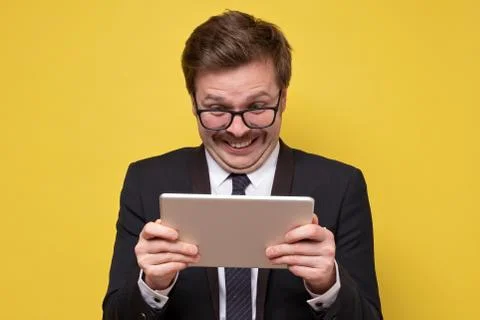 Guy in glasses holding using digital tablet looking shocked about social medi Stock Photos